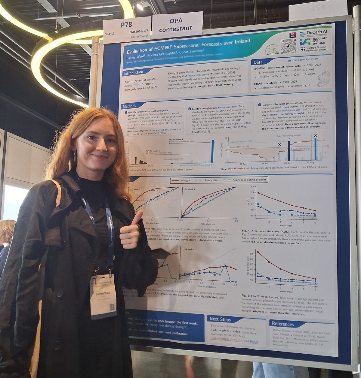Lainey giving a thumbs up beside her EMS 2026 poster