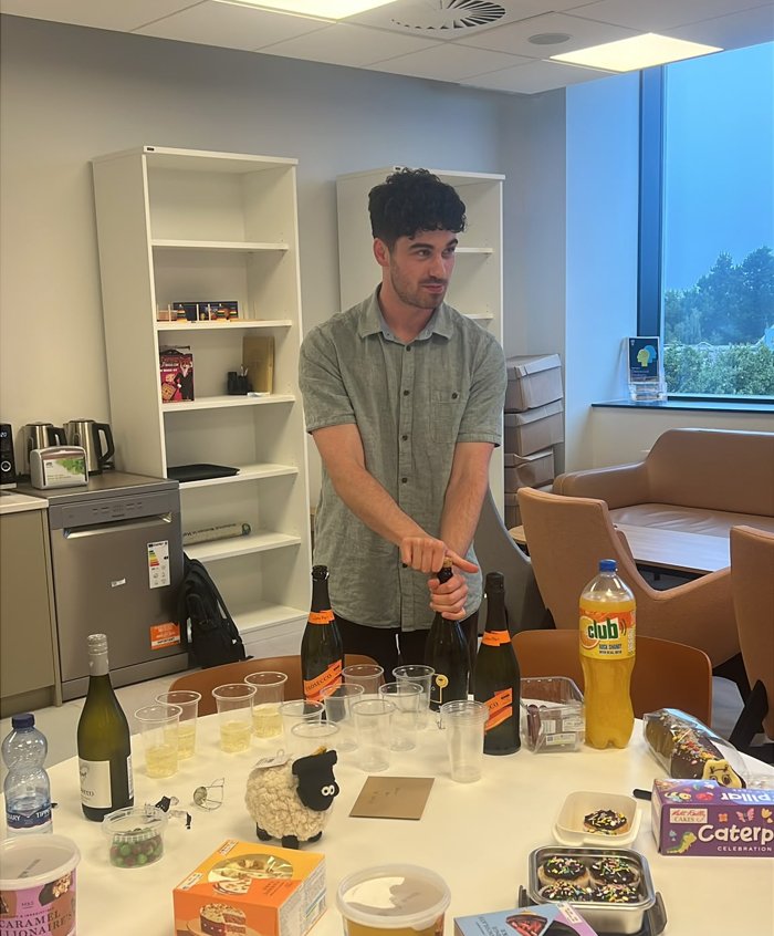 Brian Skelly opening a bottle at a celebration in the common room